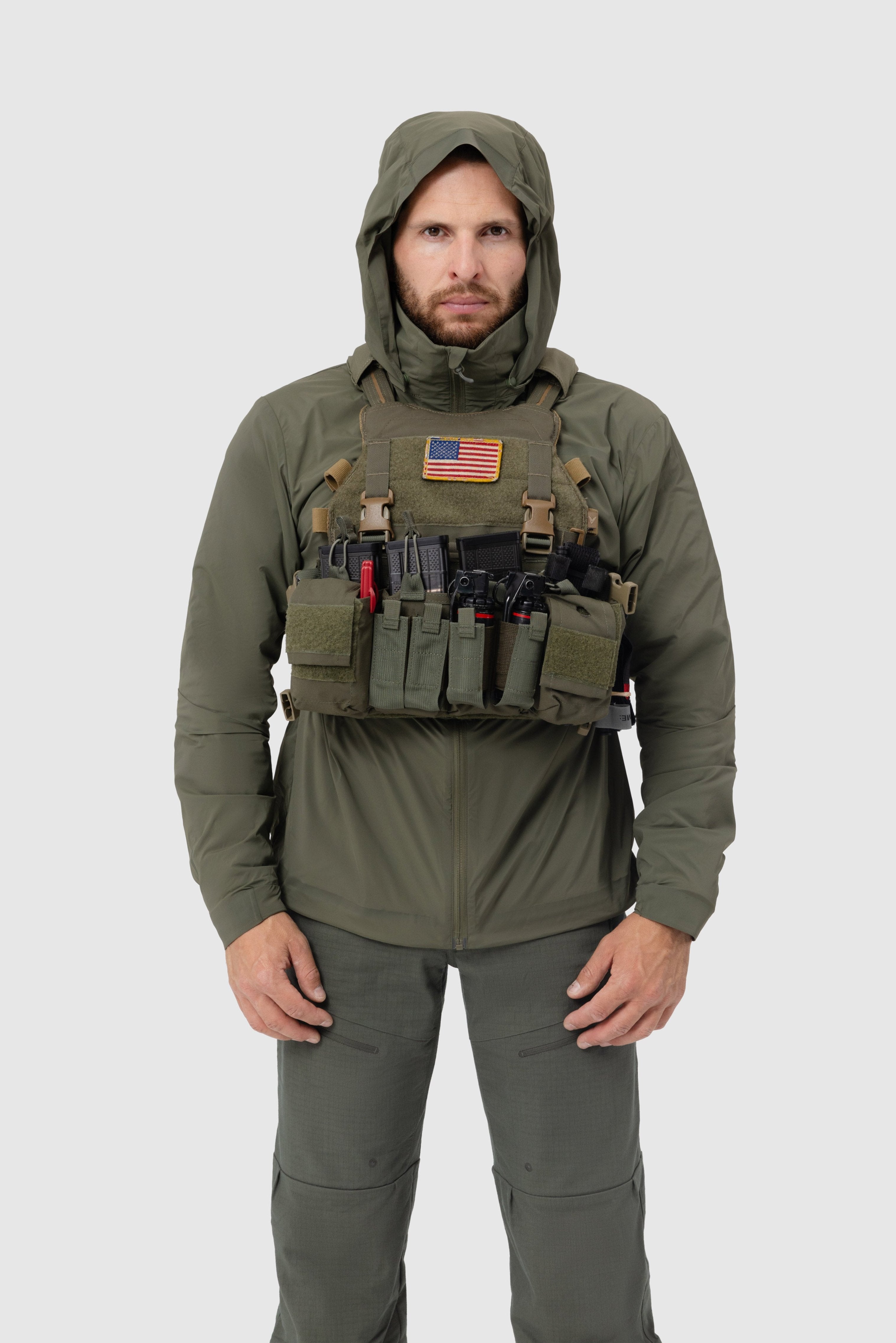 Frontal photo of the Tomahawk Performance Crosswind Jacket, a tactical windbreaker, worn under a carrier in Ranger Green color way.