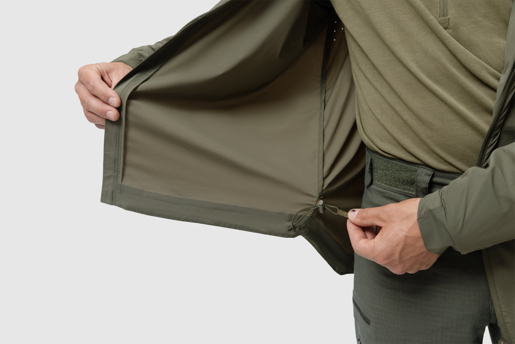 Photo of the Tomahawk Performance Crosswind Jacket's interior lining around the hem including adjustable hem drawstring in Ranger Green color way. Laser perforation for ventilation also shown.