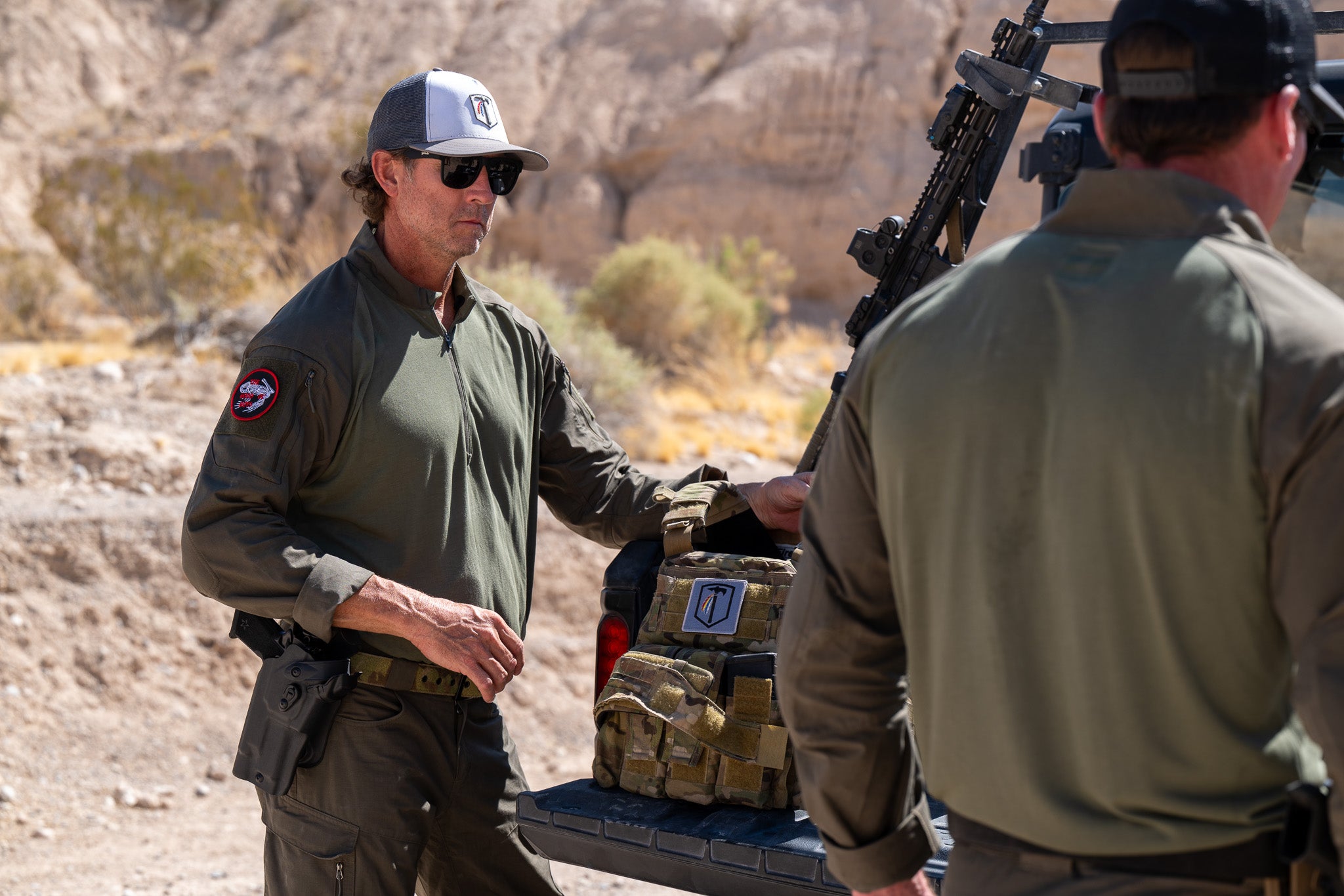 Photo of a man wearing the Tomahawk Performance HW / Combat Uniform putting on an S&S plate carrier.